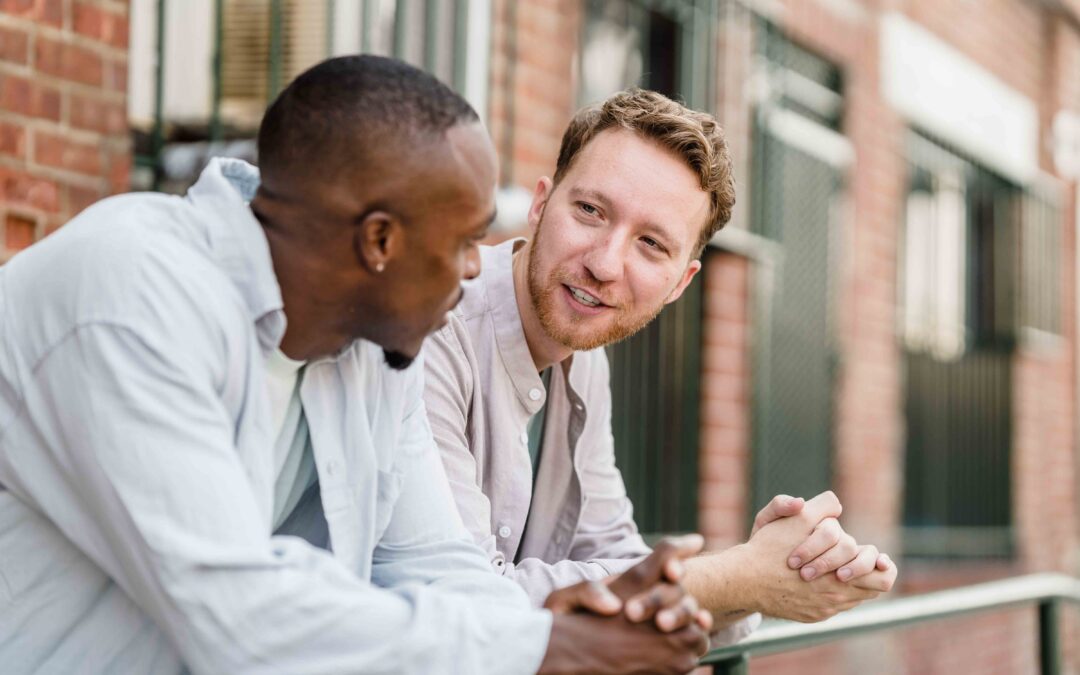 Two men engaged in conversation while sitting on a park bench, surrounded by greenery